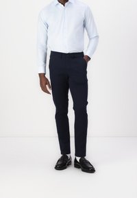 Světle modrá košile na knoflíky, námořnické kalhoty a černé společenské boty. Slim fit, hladká textura s jemn ým vzorem na košili.