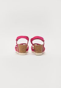 Sandali con tacco a cuneo rosa, con tomaia in suede e tacco in sughero. Presentano una strap alla caviglia e una soletta con una sottile texture. Suola platform per un supporto migliore.