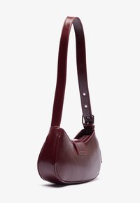 Burgundyfargene Ledertasche mit glatter Textur, geschwungener Form, verstellbarem Trageriemen und einem Reißverschluss oben.