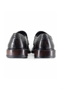 Scarpe eleganti in pelle nera con una superficie liscia, dettagli brogue e tacchi in legno sovrapposti. Mostrate dalla vista posteriore.