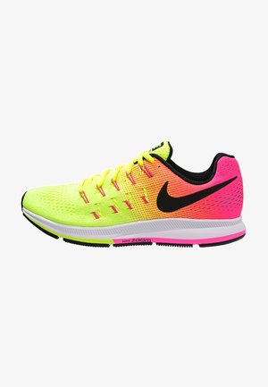 Zapatilla deportiva en amarillo neón y rosa con acentos en negro, parte superior de malla y superficie texturizada. Presenta una suela blanca con un logo verde y rosa.