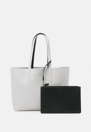 Grand sac fourre-tout blanc avec des anses fines et une pochette noire détachable au motif crocodile. Matière lisse avec un minimum de détails.