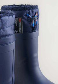 Bottes en caoutchouc navy avec un revers textile. Présentent une fermeture à cordon et une isolation 3M Thinsulate. Conception résistante à l'eau et isolante.