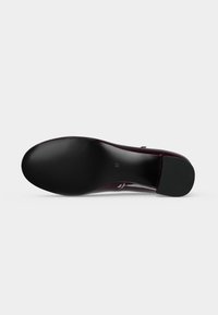 Semelle d'une chaussure sombre et brillante avec un dessous noir lisse et un talon carré, taille 37 marquée au centre.