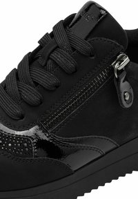 Basket noire avec un mélange de textures mates et brillantes, lacets ronds, détail de fermeture éclair sur le côté et petits clous décoratifs le long du design.