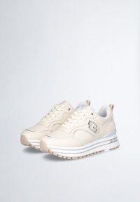 Sneaker in pelle beige con punta arrotondata, chiusura con lacci, dettagli argentati e suola in gomma testurizzata con motivo a strisce.