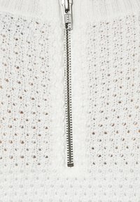 Witte gebreide trui met een rits aan de voorkant, textuurstof met open steekpatronen en een geribbelde kraag. YKK rits hardware.
