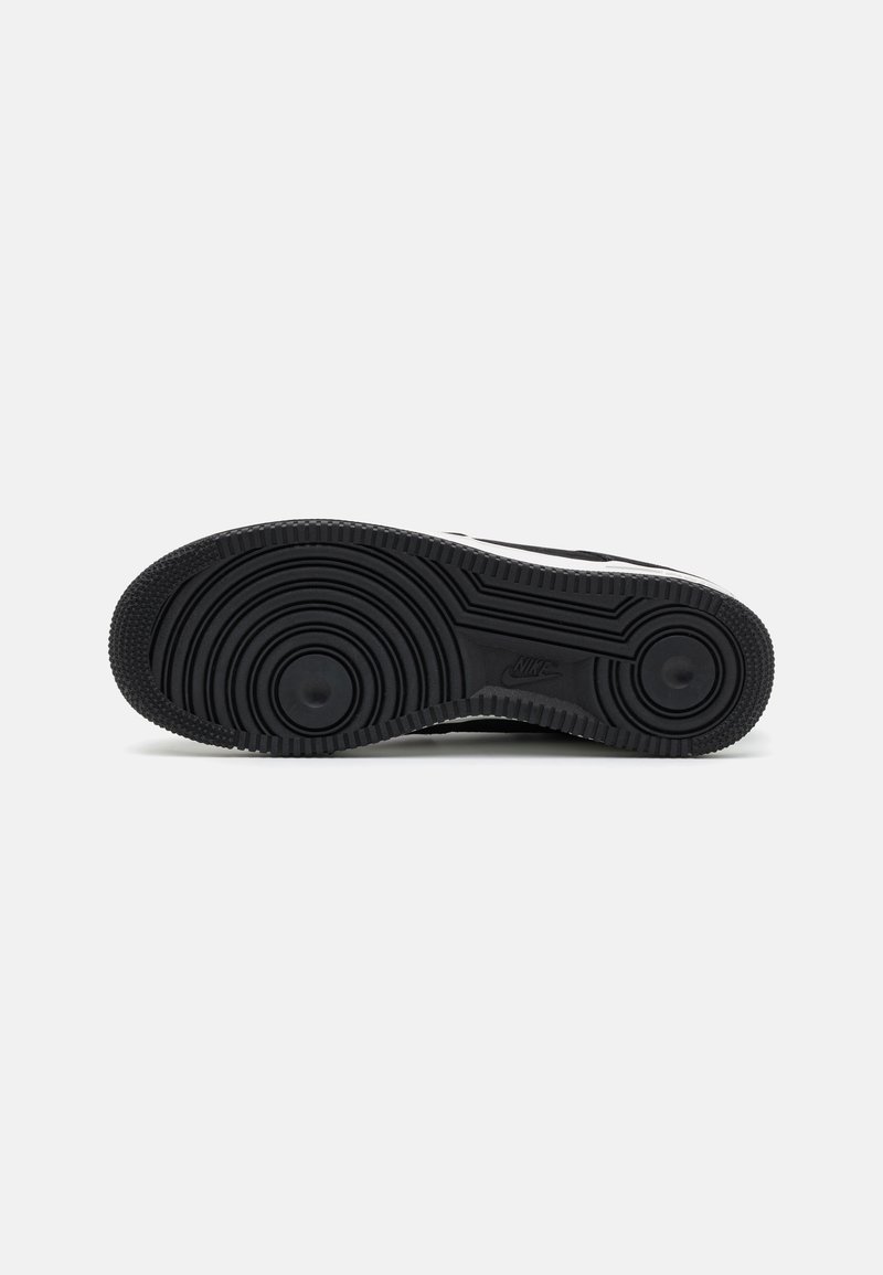 Zwarte rubberen sneakerzool met een gestructureerd, cirkelvormig loopvlakpatroon en een gladde rand. Het logo is in de zijkant geperst.