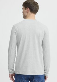 Long-sleeve gray t-shirt, soft cotton material, round neckline, fitted silhouette, smooth texture, seamless shoulders, plain design.
