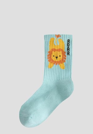 Helle blaue gerippte Socke mit einem orangen Löwengrafik auf der Vorderseite und dem Wort "ROAR" daneben. Weicher Stoff, mittellange Höhe bis zur Wade.