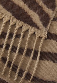 Brun og beige mønstret tørklæde med en blød uldtekstur, der har en zigzag-fringe detalje langs en kant.