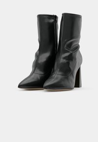 Black ankle boots made of shiny leather, featuring a pointed toe, side zipper, and chunky heel with a smooth texture and subtle stitching.