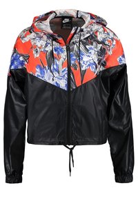 Zkrácená bunda Nike s černým podkladem a živým květinovým potiskem v červené, modré a černé barvě. Obsahuje kapuci a nastavitelný lem.