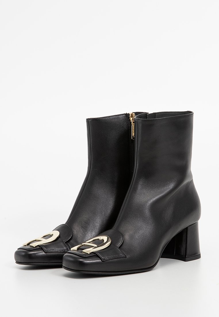 Stivali alla caviglia in pelle nera con punta quadrata, zip laterale e un accento decorativo in metallo color oro sul davanti. Design con tacco a blocco.
