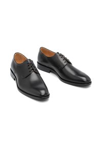 Oxfords din piele neagră, cu vârf ascuțit, cusături minime, șireturi cu trei deschideri și o textură netedă.