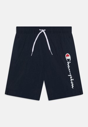 Calções de banho azul marinho feitos de um tecido leve, com cordão branco, bolsos laterais e um logo "Champion" branco com um acento vermelho.