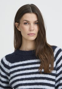 Pull en tricot rayé avec des nuances de bleu marine et de bleu clair, encolure ronde et tissu à texture douce. Rayures horizontales visibles et poignets côtelés.