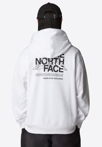 Sudadera blanca con capucha que presenta un estampado gráfico negro en la parte posterior con texto y un motivo de montaña. Puños y dobladillo de canalé. Tejido de mezcla de algodón.