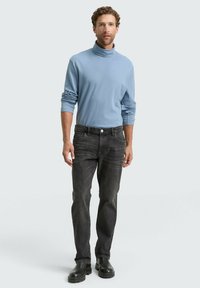 Hellblauer Rollkragenpullover, graue Jeans und schwarze Knöchelstiefel. Der Pullover hat lange Ärmel und einen entspannten Schnitt. Die Jeans haben einen klassischen Stil.