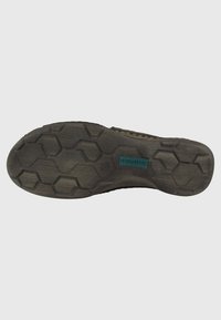Sole di calzature realizzata in materiale gommoso con un motivo a trama esagonale. Il colore è prevalentemente scuro con una finitura testurizzata e un marchio di colore teal.