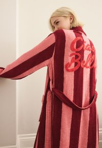 Striped bathrobe in alternating deep red and light pink. Features "Ciao Bella" in raised red lettering on the back. Soft, textured fabric.
