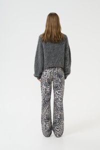 Maglione grigio morbido con un fit oversize, abbinato a pantaloni a zampa d'elefante con motivo a macchie leopardate in bianco e grigio. Texture morbida e design a gamba ampia.