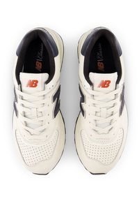 Vita sneakers med marinblå detaljer, läder- och nätmaterial, perforerad design på tån, platta snören och en framträdande vit logotyp på sidan.