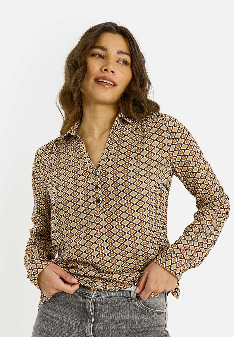 Camisa abotonada con un estampado geométrico en marrón, amarillo y blanco. Mangas largas con cuello, fabricada en una tela ligera.
