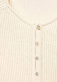 Cárdigan de punto acanalado en crema con escote en V y cinco botones claros en la parte delantera, con una tela suave y texturizada.