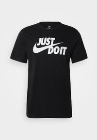 Sort bomuld T-shirt med korte ærmer, med en stor hvid "Just Do It"-logo og Nike swoosh foran. Enkel rundhalsdesign.