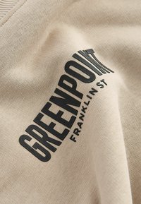 Bežna pamučna tkanina ima istaknuti crni grafički tekst s natpisom "GREENPOINT FRANKLIN ST." Glatka tekstura s laganim rastezanjem.