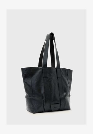 Czarna skórzana torba typu tote z podwójnymi paskami na ramię i subtelnym fakturowanym wzorem, stojąca pionowo na jednolitym szarym tle.