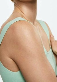 Débardeur vert menthe avec des bretelles larges, un col arrondi et une texture ajustée qui épousent les formes du corps. Fini en tissu lisse visible.
