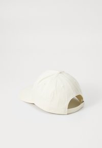 Hvid bomulds-baseballkasket med en buet skygge, justerbar rem og ventilationshuller. Simple design med en glat tekstur og minimal detaljering.