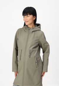 Maslinasta zeleni softshell jakna s kapuljačom, zatvaranjem na zip, podesivom pričvršćenom u struku i dva prednja džepa s šnalom. Glatka tekstura.