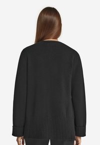 Czarny dziany sweter z ribbowym wykończeniem na dole i mankietach, charakteryzujący się luźnym krojem i prostą sylwetką, minimalnymi detalami oraz gładką teksturą.