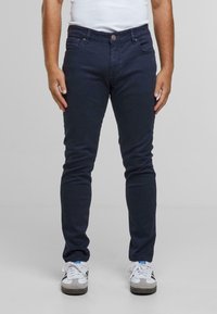 Námořnické skinny džíny s hladkým povrchem, obsahující pět kapes, zapínání na přední knoflík a jemné detaily šití.