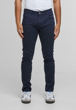 Navy skinny jeans with a smooth texture, featuring five pockets, front button closure, and subtle stitching detail.