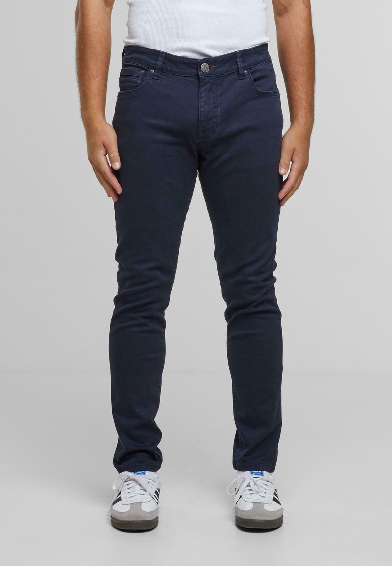 Námořnické skinny džíny s hladkým povrchem, obsahující pět kapes, zapínání na přední knoflík a jemné detaily šití.