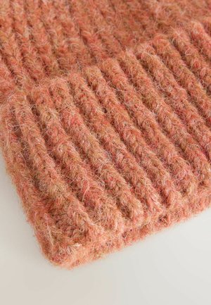 Stickad accessoar i mjukt, texturerat garn med en ögldesign. Färgerna varierar från persika till mjuk rosa. Tjock, varm och mysig utseende.