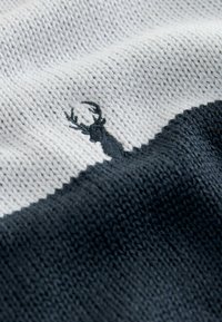 Knit textile in alternating light gray and dark gray sections, featuring a black embroidered deer silhouette against the lighter fabric.