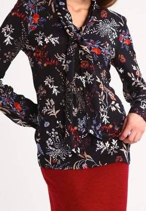 Blusa floreale nera con scollatura a fiocco, caratterizzata da vivaci motivi floreali rossi, blu e bianchi. Maniche lunghe con vestibilità comoda.