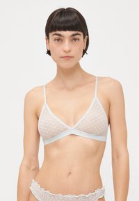 Bela trikotna bralette iz polka dot mrežaste tkanine, z čipkastim robom in tankimi nastavljivimi naramnicami. Mehak material in minimalistični oblikovni detajli.