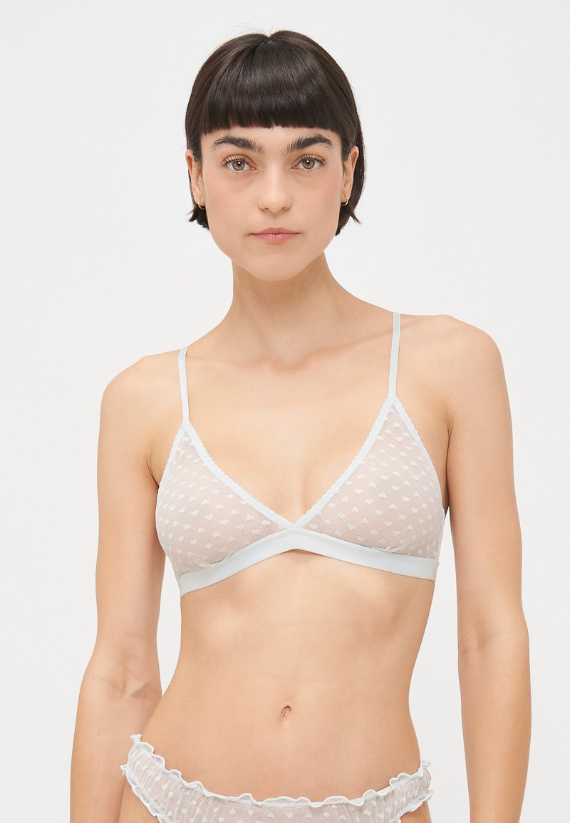 Bela trikotna bralette iz polka dot mrežaste tkanine, z čipkastim robom in tankimi nastavljivimi naramnicami. Mehak material in minimalistični oblikovni detajli.
