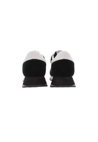 Sneaker in bianco e nero con esterno in suede e sintetico liscio, dotate di una suola nera spessa e un design del tallone arrotondato.
