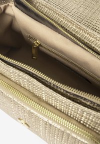Sac à main texturé doré avec plusieurs compartiments zippés, intérieur en tissu beige et accents métalliques dorés.