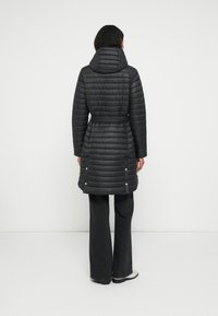 Czarna puchowa kurtka z dopasowaną talią, kapturem i poziomym pikowaniem. Posiada zatrzaski na dole oraz gładką, błyszczącą teksturę.