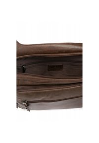 Interno di una borsa in pelle marrone con numerose tasche con cerniera. Materiale testurizzato con una finitura liscia. Marchiatura sottile visibile sulla fodera.