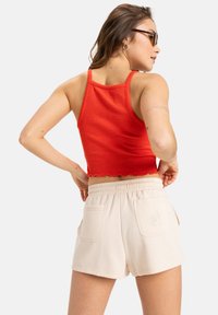 Red ribbed crop top with scalloped hem, paired with cream elastic-waist shorts featuring back pockets and subtle embroidered design.