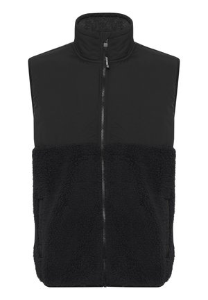 Zwarte vest met een hoge kraag, voorzien van een gladde bovenkant en een zachte, textuurrijke onderzijde. Middenvoor een rits en zijzakken.